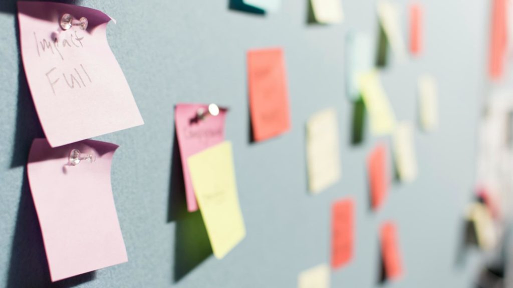 Wall of sticky notes with one note showing the words "Impact Full"